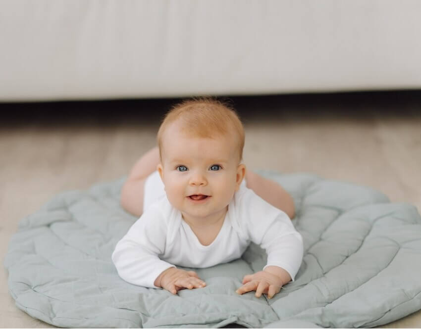Bébé sur un tapis gris en forme de feuille